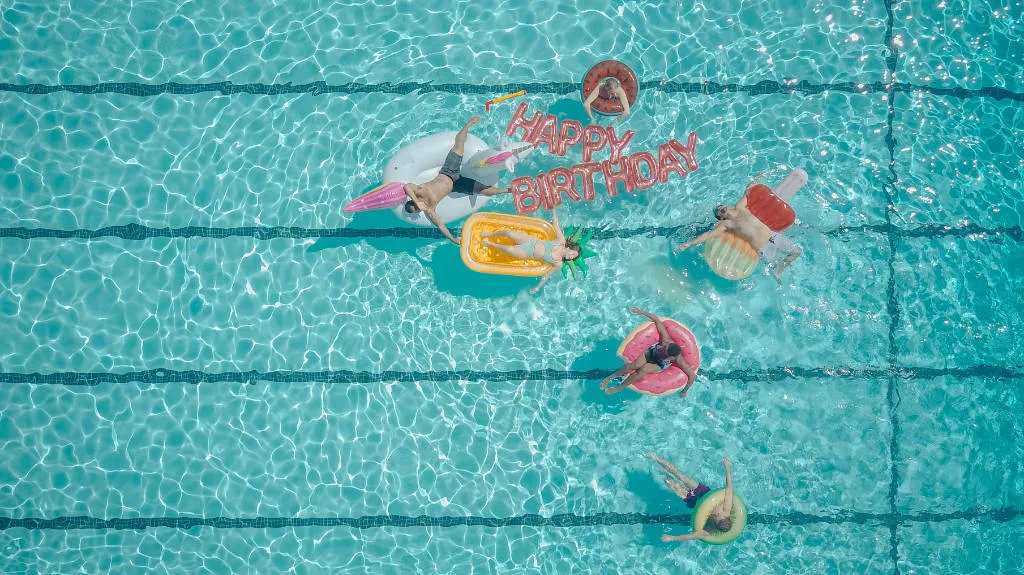 Personnes flottant sur des bouées dans une piscine lors d'un anniversaire