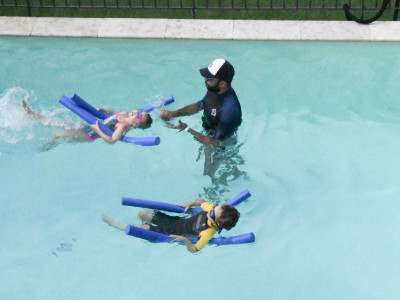 Maître-Baigneur lors d'un cours en petit groupe avec enfants nageant sur le dos 