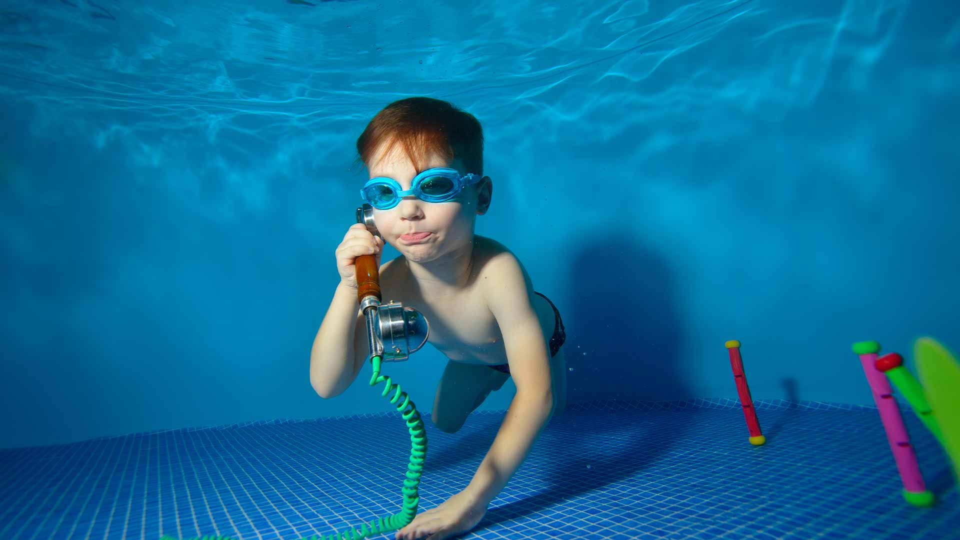 Garçon sous l'eau tenant un téléphone près de son oreille